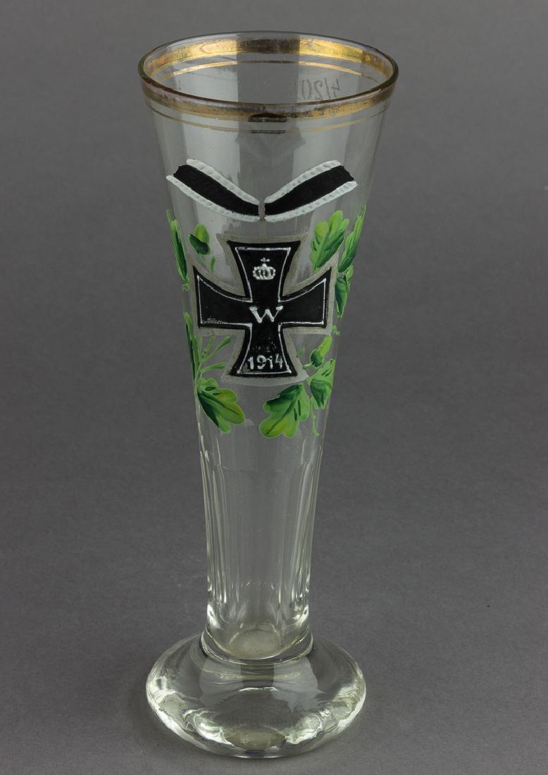 WORLD WAR I IRON CROSS BEER GLASS: WORLD WAR I IRON CROSS BEER GLASS A World War I-period beer glass, approx. 8 1/2" x 3" dia., hand-painted in high relief with a 1914-dated iron cross, suspended from a ribbon and surrounded by oak bou