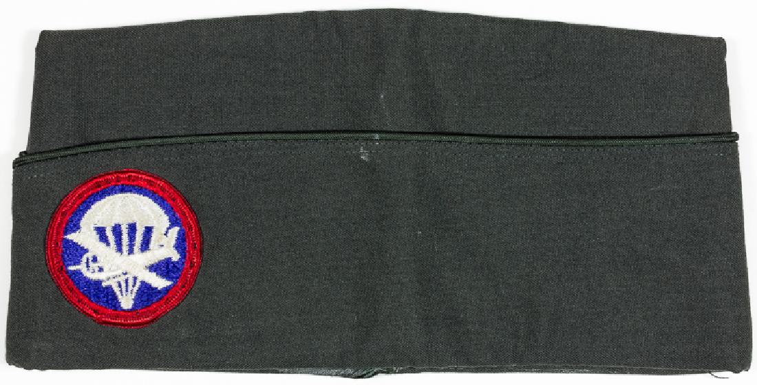 GARRISON CAP WITH GLIDER PATCH: GARRISON CAP WITH GLIDER PATCH American garrison cap, dark green with dark green piping, bears a circular glider patch affixed on left side. Owner has penned his name "Sheringham" within. Very good.