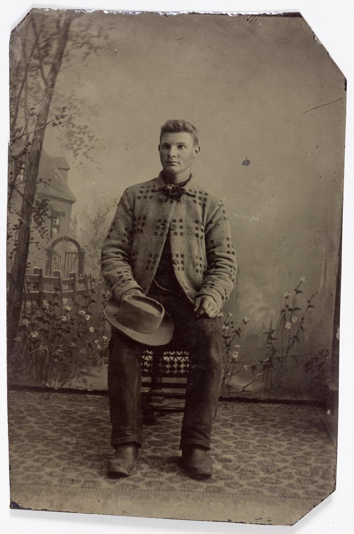 COWBOY TINTYPE: COWBOY TINTYPE Small tintype depicting a cowboy, 2 Â¼" x 3 Â½", shows the man full-length and seated wearing a western-style coat, boots, and a western hat upon his knee. Very good.