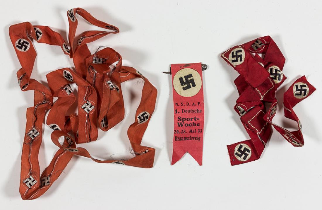 MACHINE-EMBROIDERED SWASTIKAS: MACHINE-EMBROIDERED SWASTIKAS 45 1/2" red rayon ribbon, machine-embroidered with thirty mobile swastikas within white disks. These would likely have been cut and applied to uniforms. Also present is a