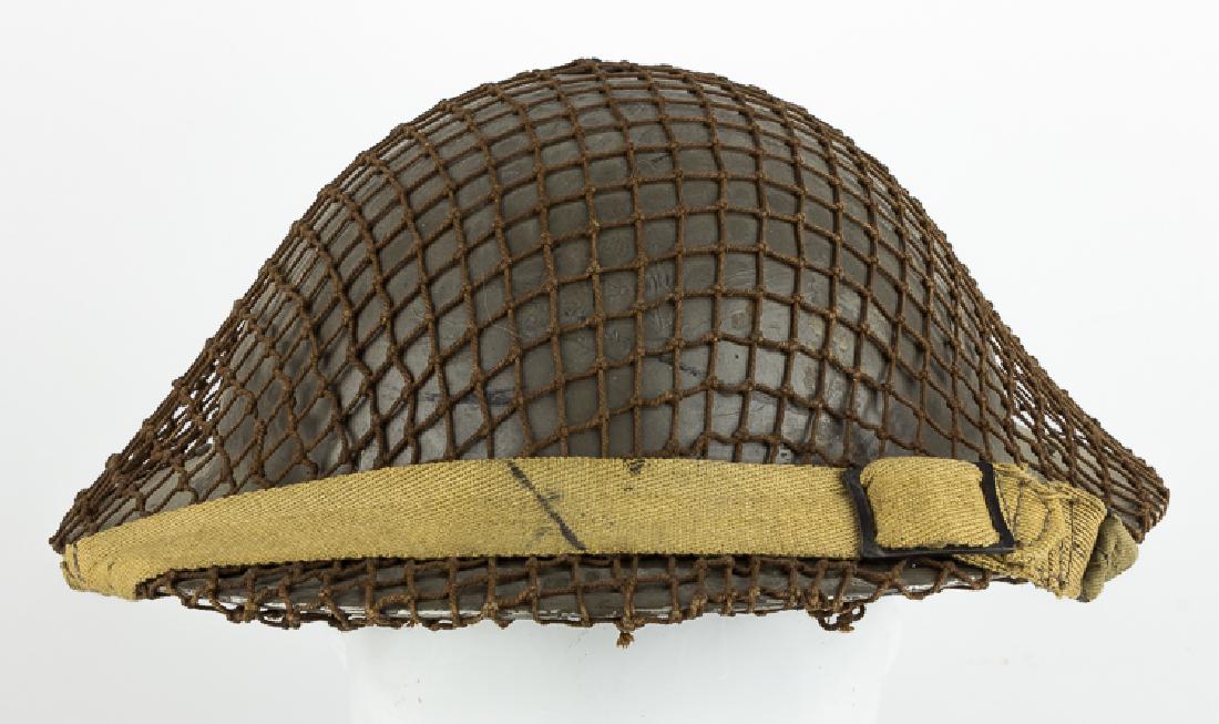 BRITISH "BRODIE" HELMET: BRITISH "BRODIE" HELMET British Brodie helmet, fitted with elsaticized chin strap, rubber padding and rubberized liner, stamp-dated "1940", with possibly post-war camo netting. Overall very good to fi