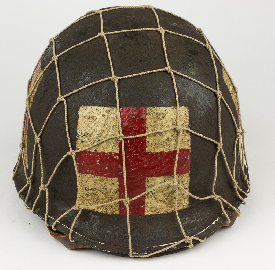 AMERICAN MEDIC'S M1 HELMET: AMERICAN MEDIC'S M1 HELMET World War II-era steel M1 helmet with swivel strap bales and a front-facing seam, indicating manufacture between 1943 and 1945. The exterior bears a very heavy, dark green c