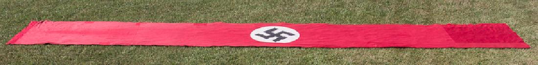 NSDAP GAULEITUNG FLAG: NSDAP GAULEITUNG FLAG Very large NSDAP flag, 39' x 5', the red field constructed from multiple sections of cloth, with a sewn black fabric mobile swastika applied to a white disk at center. A red fabr