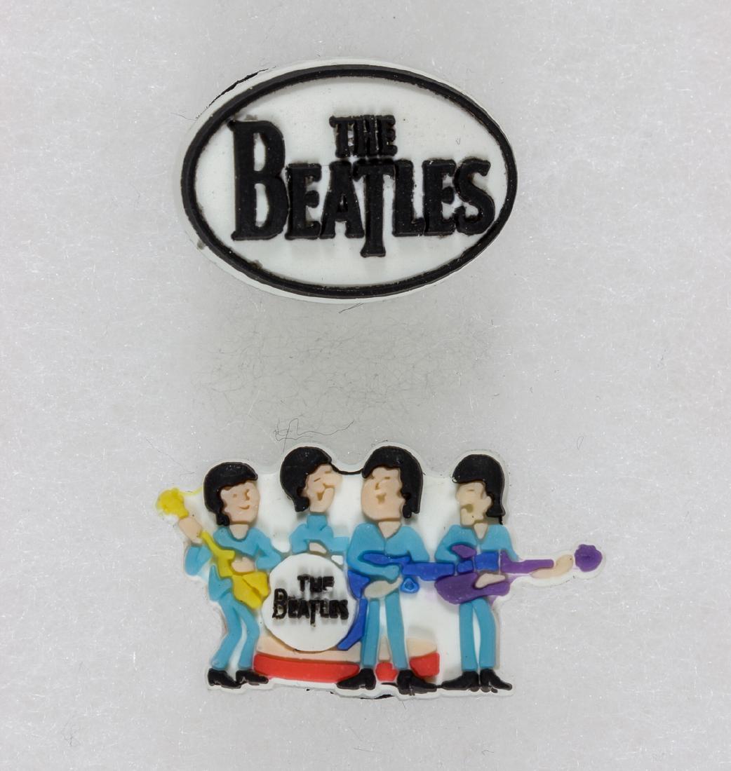 (BEATLES) NYBRO BEATLE CARTOON PIN - ONE OF FIFTY MADE: Excessively rare pin bearing a cartoon image of the four Beatles, along with a second pin bearing the Beatles logo. The pins were made by Swedish crystal manufacturer Nybro and intended to be worn as 