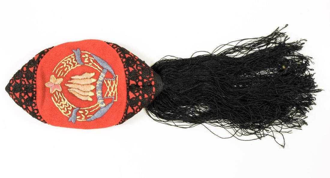 YUGOSLAVIAN "LIKA" CAP WITH ANTI-FASCIST COUNCIL EMBLEM: Vintage Yugoslavian "Lika" cap constructed of red wool and cloth, decorated with black thread embroidery around the edge and with a tassel of black silk thread at the rear. The crown is hand-embroider