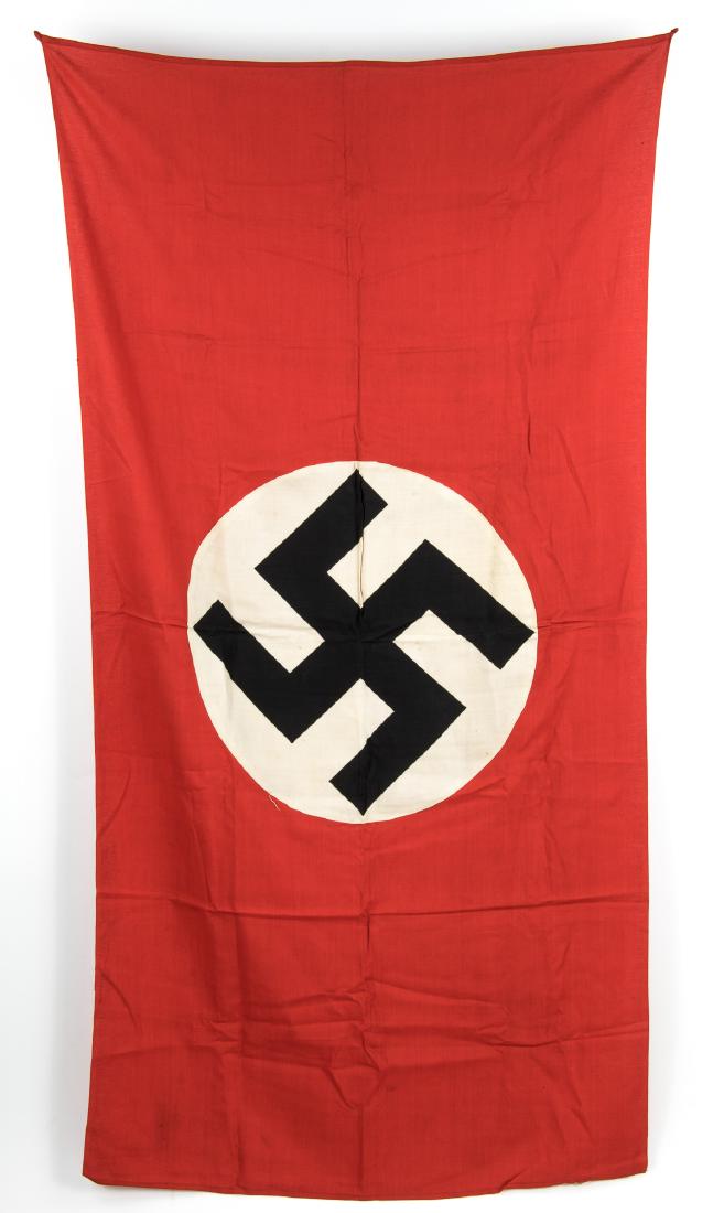NSDAP FLAG WITH CLOTH LOOPS: Unusual NSDAP cotton flag, 56" x 29". Two-piece construction with the flag body to which is sewn on both sides a white circular field with black printed mobile swastika. The flag bears two small cloth