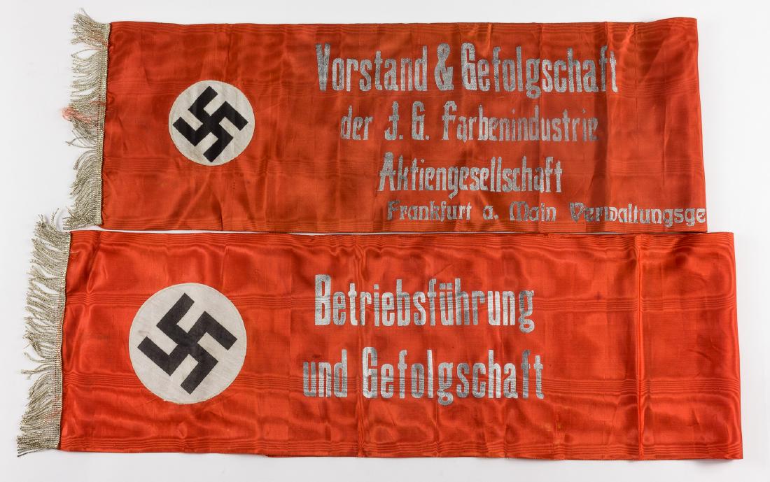 I.G. FARBEN FUNERAL SASH: Red rayon sash, 51 1/2" x 10 1/2", with braided silver wire fringe at one end, and bearing a 4 1/4" dia. roundel with a mobile swastika. The sash further bears the inscription "Vorstand & Gefolgschaft