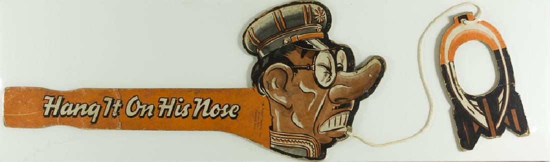 ANTI-TOJO "RING TOSS" GAME: Excellent American World War II "ring toss" game, approx. 13 Â½" x 6", consisting of a paperboard handle with a very unflattering cartoon caricature of Hideki Tojo, with the title "Hang It On His No