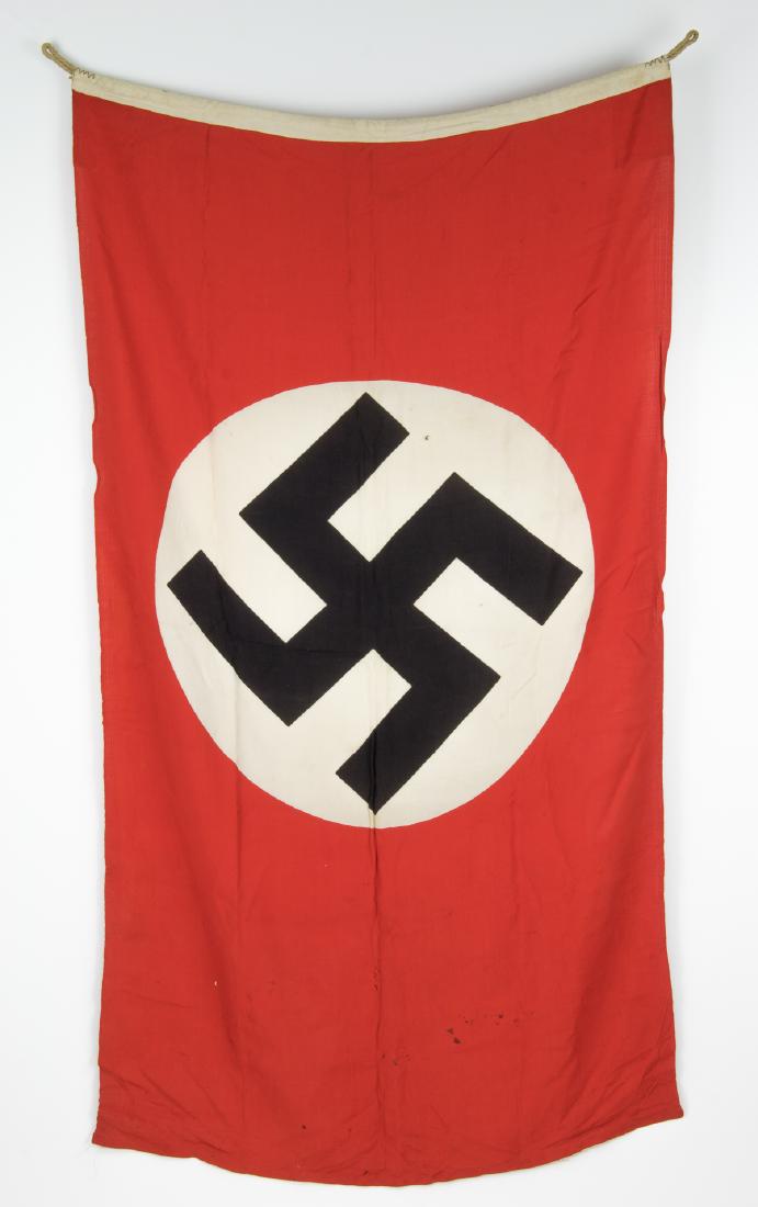 THIRD REICH NAVAL JACK: Smaller Kreigsmarine "goesch" ("naval jack"), 68" x 31 1/4", of red cotton bunting construction, clamp-dyed with a white disk and swastika at center. The hoist features an added strip of fabric stampe