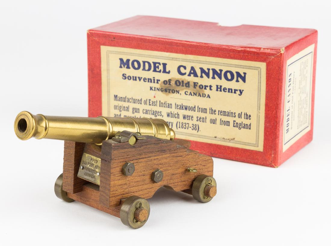FORT HENRY GUN CARRIAGE RELIC: A neat relic from Fort Henry in Kingston, Ontario, a 6" long brass and teak replica of a cannon mounted at the fort ca. 1840, in the original packaging from about 1945. The package notes that the mini