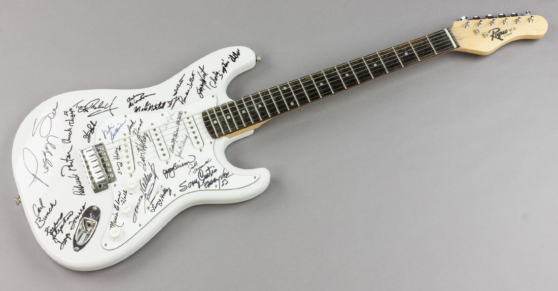 BUDDY HOLLY "PEGGY SUE" SIGNED GUITAR: White bodied Squire Rogue ST-3 six-string guitar signed by 28 individuals who performed with iconic singer-songwriter and musician BUDDY HOLLY (1936-1959). The signatures appear upon the body and pick