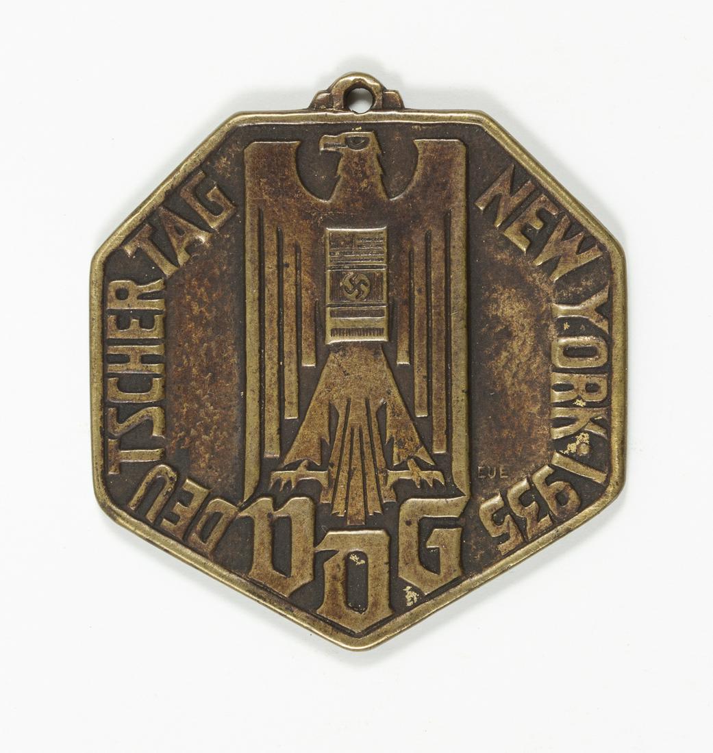 GERMAN-AMERICAN BUND FOB: Small bronze charm sold by the pro-Nazi German-American Bund, a heptagonal one-sided fob 1.25' wide and bearing an inscription in German: 'German Day New York 1935' on either side of an eagle with a s