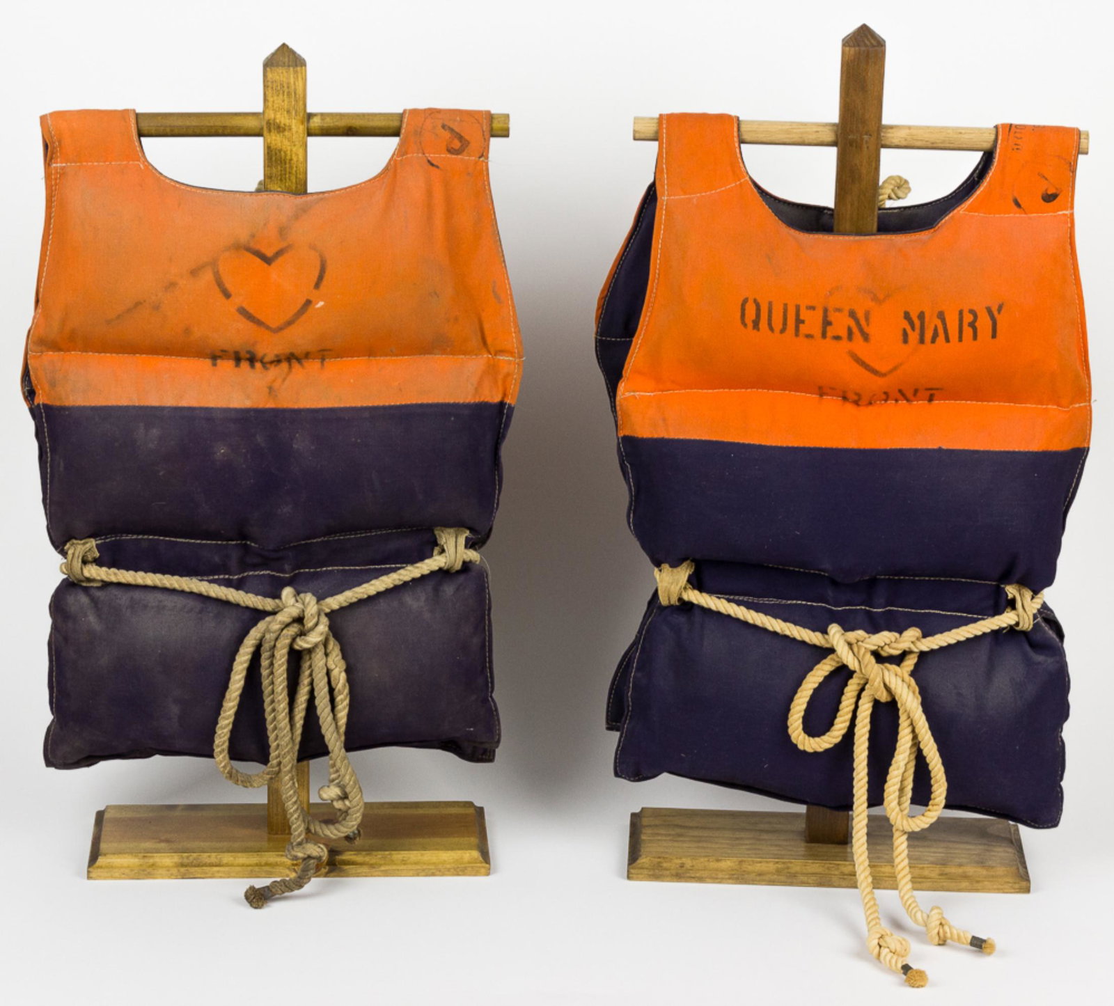 TROOP SHIP "QUEEN MARY" LIFE VESTS: Pair of original World War II-era life vests taken from the most notable troop transport of the conflict, the ocean liner R.M.S. QUEEN MARY. The first vest, approx. 44' x 14 ½' fully opened, is