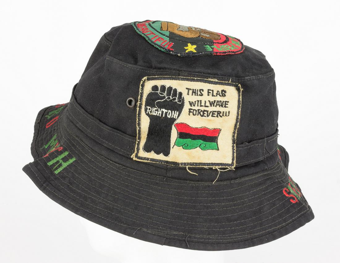 BLACK POWER BUCKET HAT: Black fabric bucket hat, featuring a hand-embroidered circular patch on the top of the crown depicting an upraised fist on a red, black and green Garvey flag, with the mottoes 'Power to the People' an