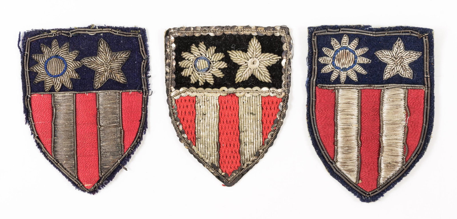 CHINA-BURMA-INDIA SHOULDER PATCHES: Fine lot of three theater-made Chine-Burma-India (CBI) shoulder patches, each 3 1/2" tall, different elaborate designs incorporating cloth, bullion, silver thread, sequins, etc., in overall very good 