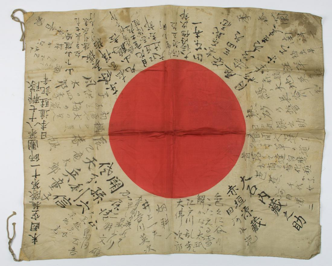 JAPANESE SOLDIER'S "GOOD LUCK" FLAG: White cotton flag 38 x 27 in. dyed with a red Japanese "meatball" symbol at center. The white field of the flag bears numerous Japanese inscriptions in black ink undoubtedly wishes for good 