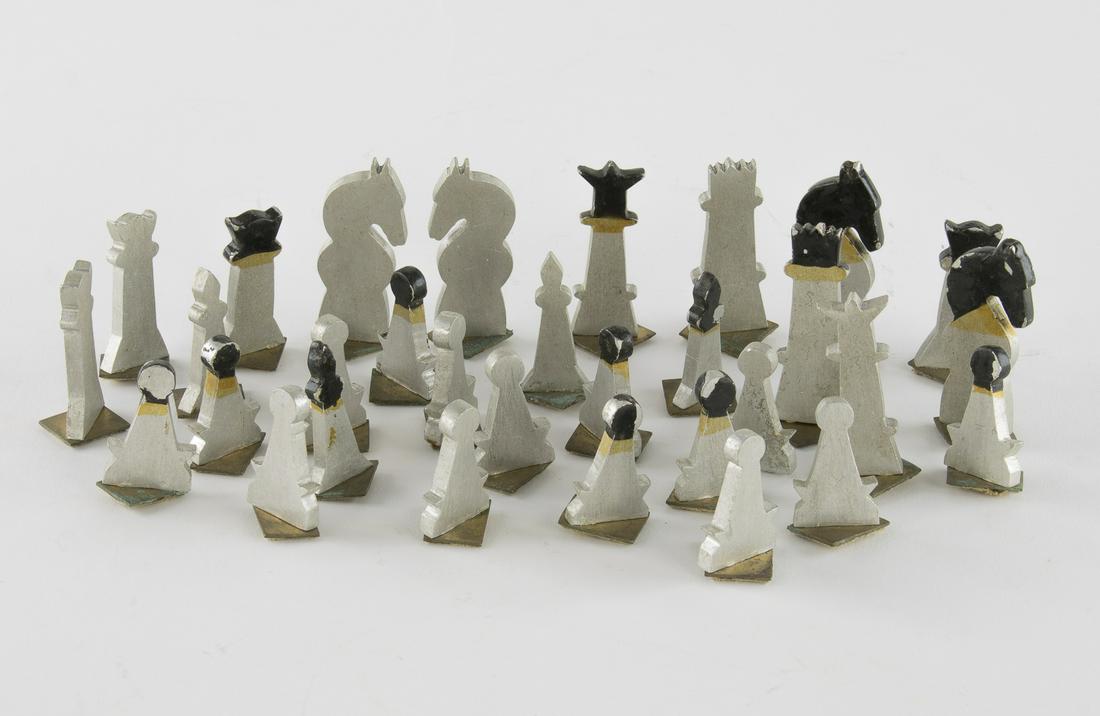 PRISONER-MADE CHESS SET FROM A RUSSIAN GULAG: Crudely-made Russian chess set undoubtedly made by a prisoner held at a Russian gulag in 1945. The 8.5 x 9 in. chess board was made of heavy gauge aluminum held together by brass braces at each corner
