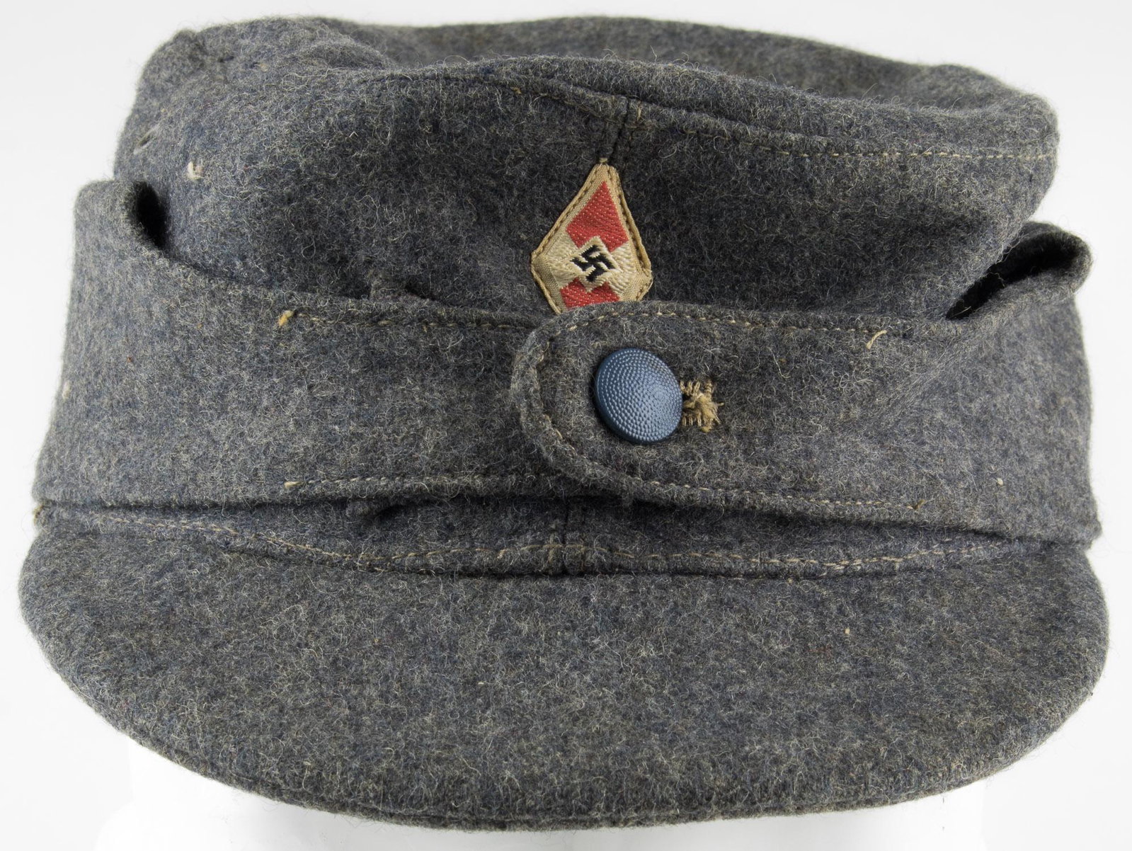 HITLER YOUTH FLAK HELPER'S WINTER CAP: Hitler Youth Flak Helper's winter cap, variant design. Luftwaffe blue wool construction with small BeVo HJ insignia machine-applied at front. One vent hole apparent on either side of the cap. Within, 