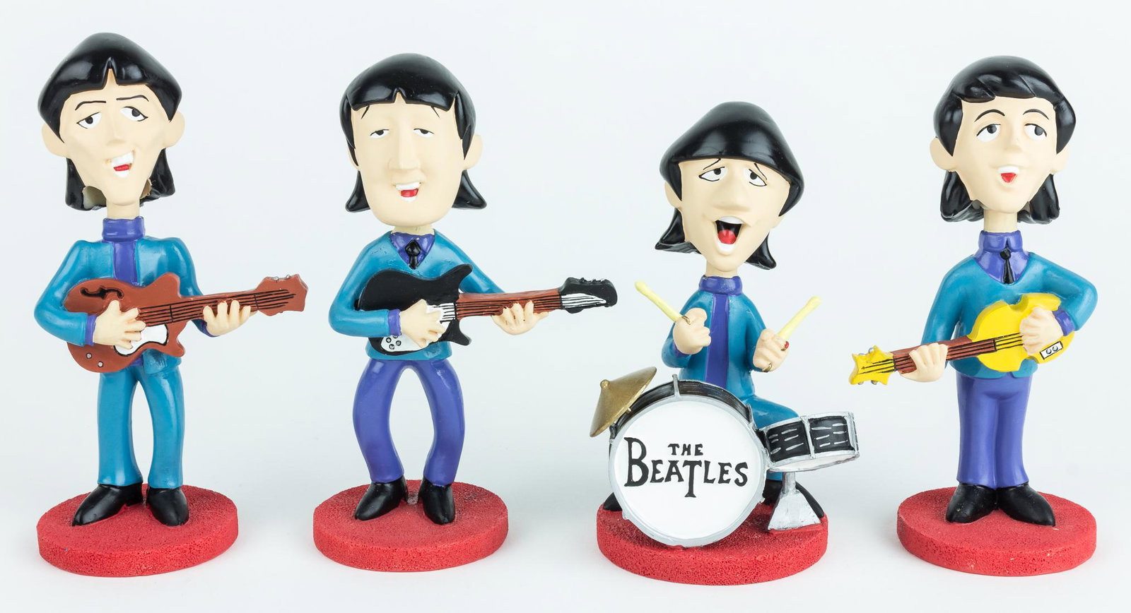 (BEATLES) BEATLES ANIMATION BOBBLE-HEAD DOLLS: Set of four 'cartoon design' Beatles 'bobble-head' dolls, each about 5.5 in. tall and made of cast resin with their respective instrument. The figures are clad in blue suits and stand on orange bases.
