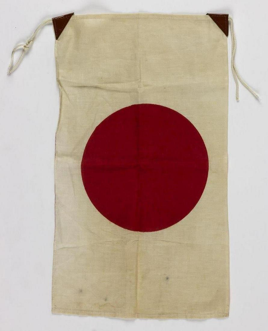 JAPANESE NATIONAL 'MEATBALL' FLAG: Small Japanese 'meatball' flag, approx. 18.5 x 11 in. cotton, clamp-dyed with a red 'hinomaru' sun symbol at center. The hoist corners are fitted with two leather tabs fitted with fabric ties. Very go