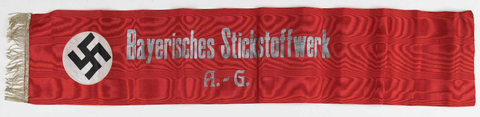 N.S.D.A.P. FUNERAL SASH: Rare red moire NSDAP funeral sash, 7.75 x 40.5 in., bearing 1.5 in. silver bullion fringe on one end. One end bears a black printed swastika on a white silk disc, which is sewn on the red field. The c