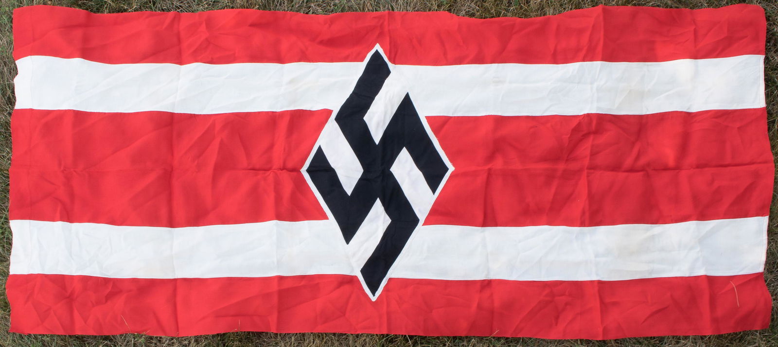 NATIONAL SOCIALIST GERMAN STUDENTS' UNION FLAG: Scarce and very large National Socialist German Students' Union flag, 41 x 92 in., double-sided, bearing a six-piece black swastika stitched to a white diamond on a red field, with two white, horizont