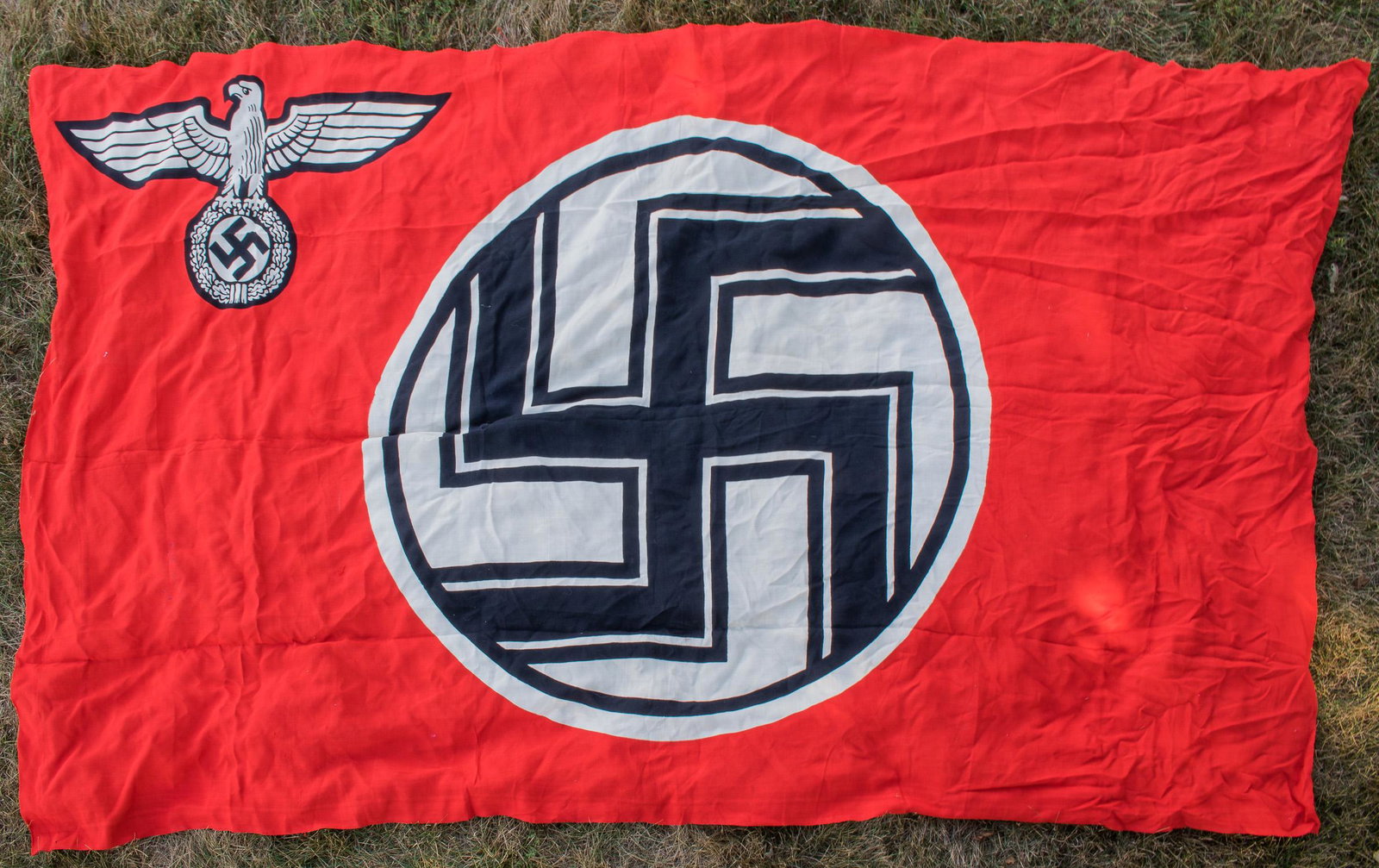 NAZI STATE SERVICE FLAG: Large Third Reich 'Reichsdienstflagge' or 'state service flag', 84 x 120 in., made of red cotton bunting, clamp-dyed with a static swastika within a white disk, with the arms of the swastika intersect