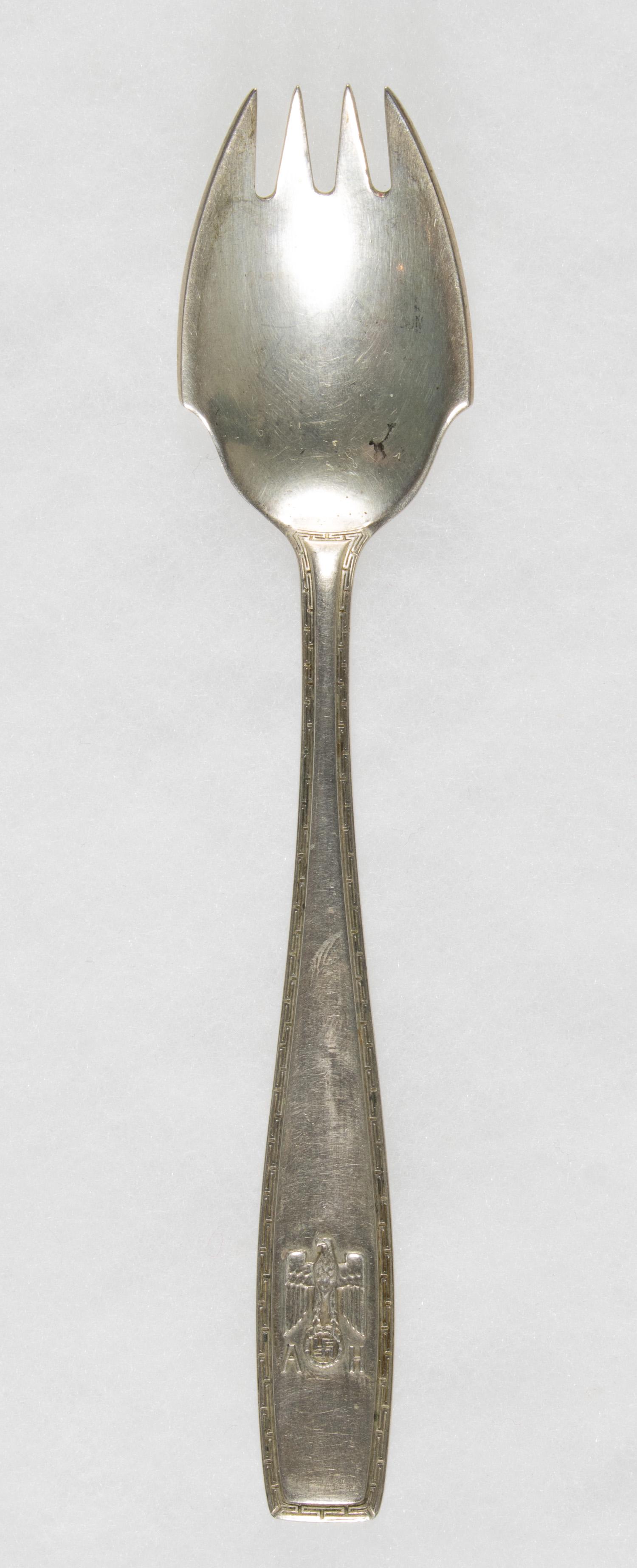 ADOLF HITLER FORMAL OYSTER FORK: Rare silver oyster fork from a personal set of Adolf Hitler's silverware, 5.5 in. The handle is bordered with the Greek key pattern, the end of the handle bearing the national eagle with swastika at b