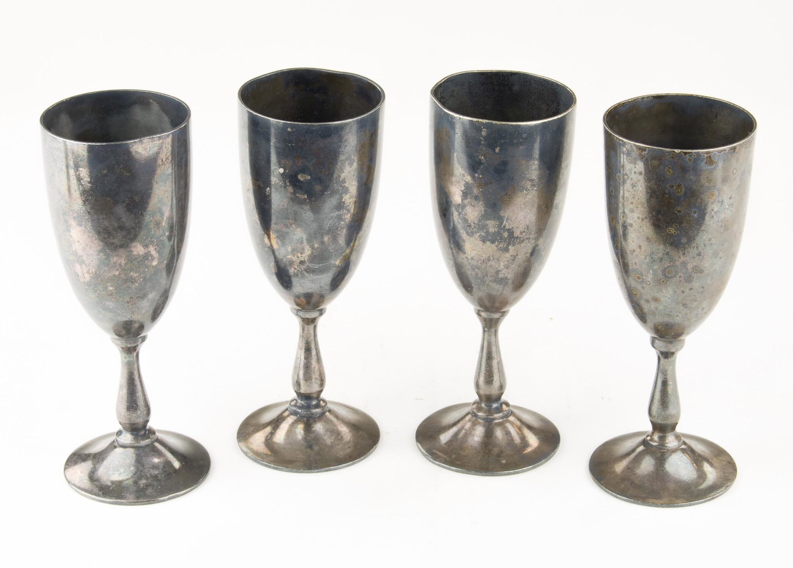 WINE GOBLETS FROM A FAVORITE HITLER HOTEL: Fine set of four heavy silver plated wine goblets, each 6.5 in. tall and 2.5 in. wide at the mouth. The bottom of each goblet bears a swastika encircled by a wreath, and the bases of three of the four