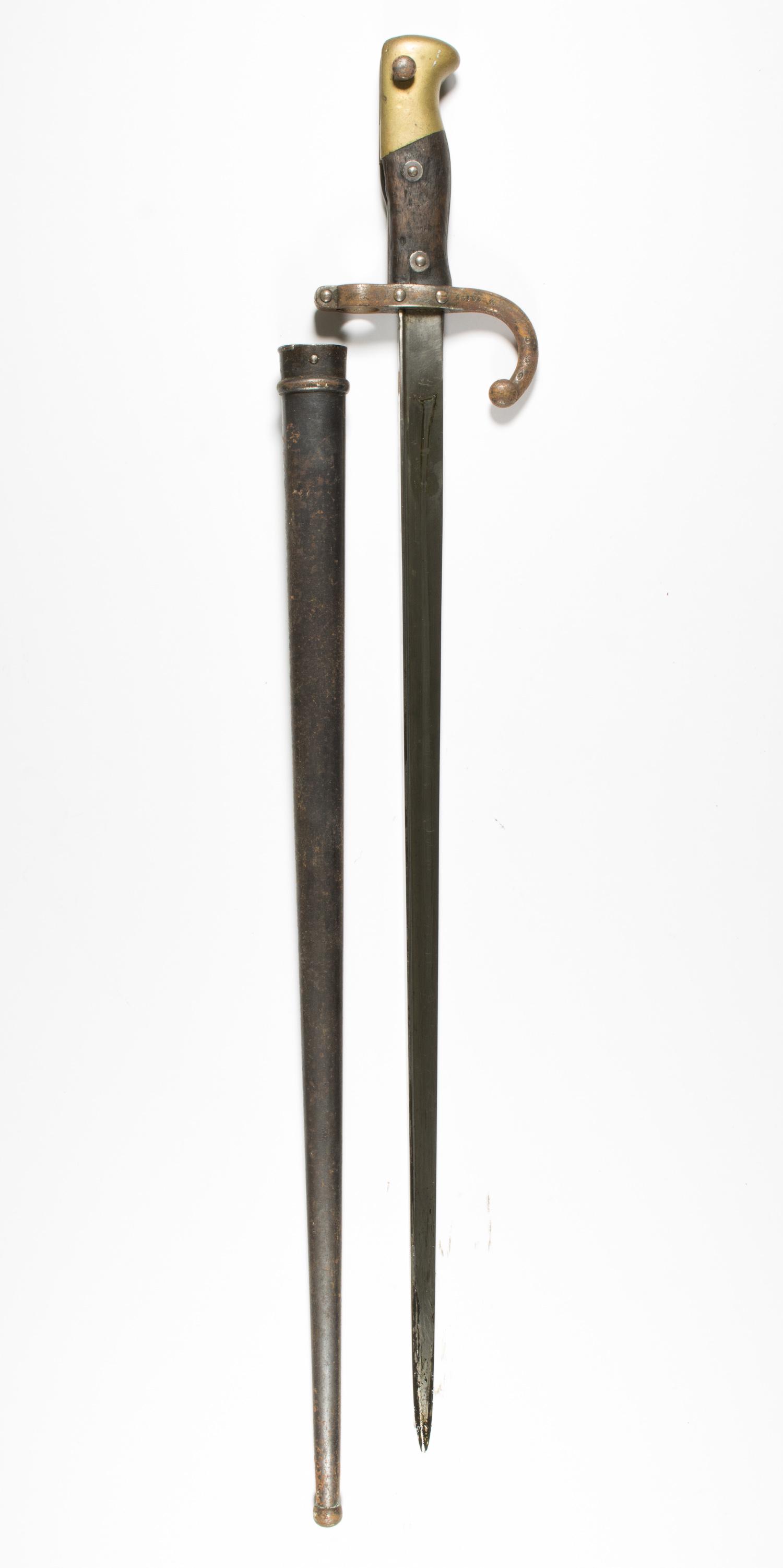 FRENCH M1874 GRAS BAYONET: A late nineteenth century French bayonet for the Gras rifle, 20.5 in. blade, 27.5 in. overall, with wood grip and curved cross guard, housed in a black metal scabbard. No maker's marks present due to 