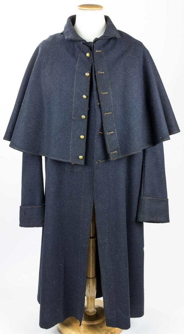EARLY MANUFACTURE UNION GREATCOAT WITH CAPE: Rare, early war Union greatcoat with integral cape in excellent condition. This federal blue wool knee-length coat the five original Waterbury Button Co. U.S. buttons at front as well as the six butto