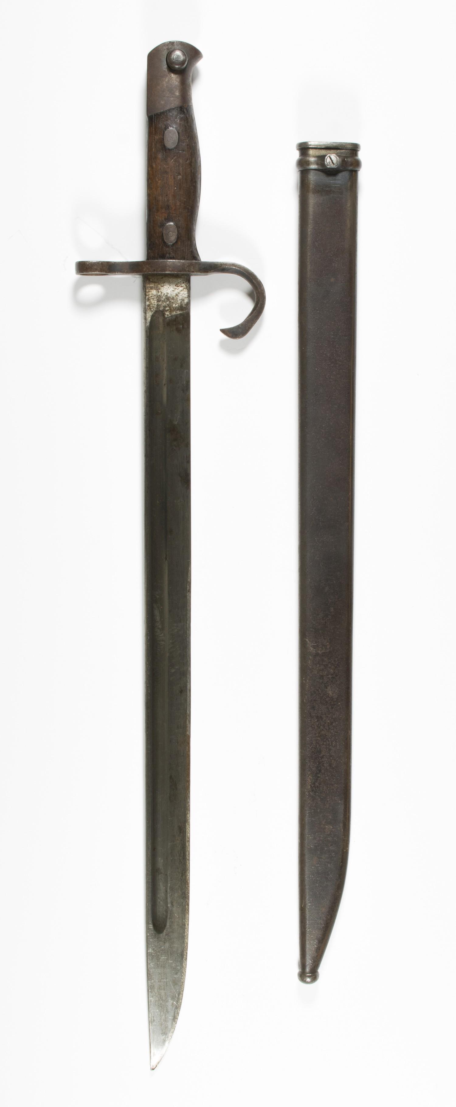 JAPANESE ARISAKA BAYONET: Japanese Arisaka straight single-fullered bayonet, steel hilt with hooked quillon, steel pommel, wood scale grips attached with rivets. Scabbard of smooth blued steel, with frog loop. Th ricasso is ma