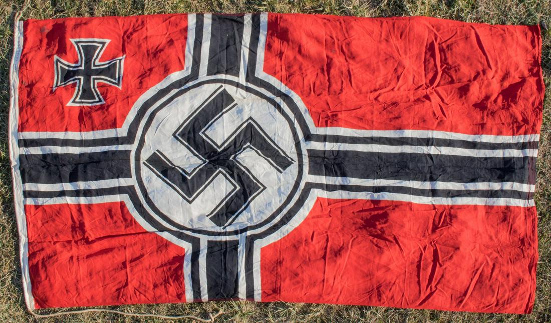 LARGE GERMAN REICHSKREIGFLAGGE: Third Reich Reichskriegsflagge, roughly 60 x 96 in., constructed of red wool bunting clamp-dyed with a black and white cross offset towards the hoist, with a black mobile swastika within a white disk 