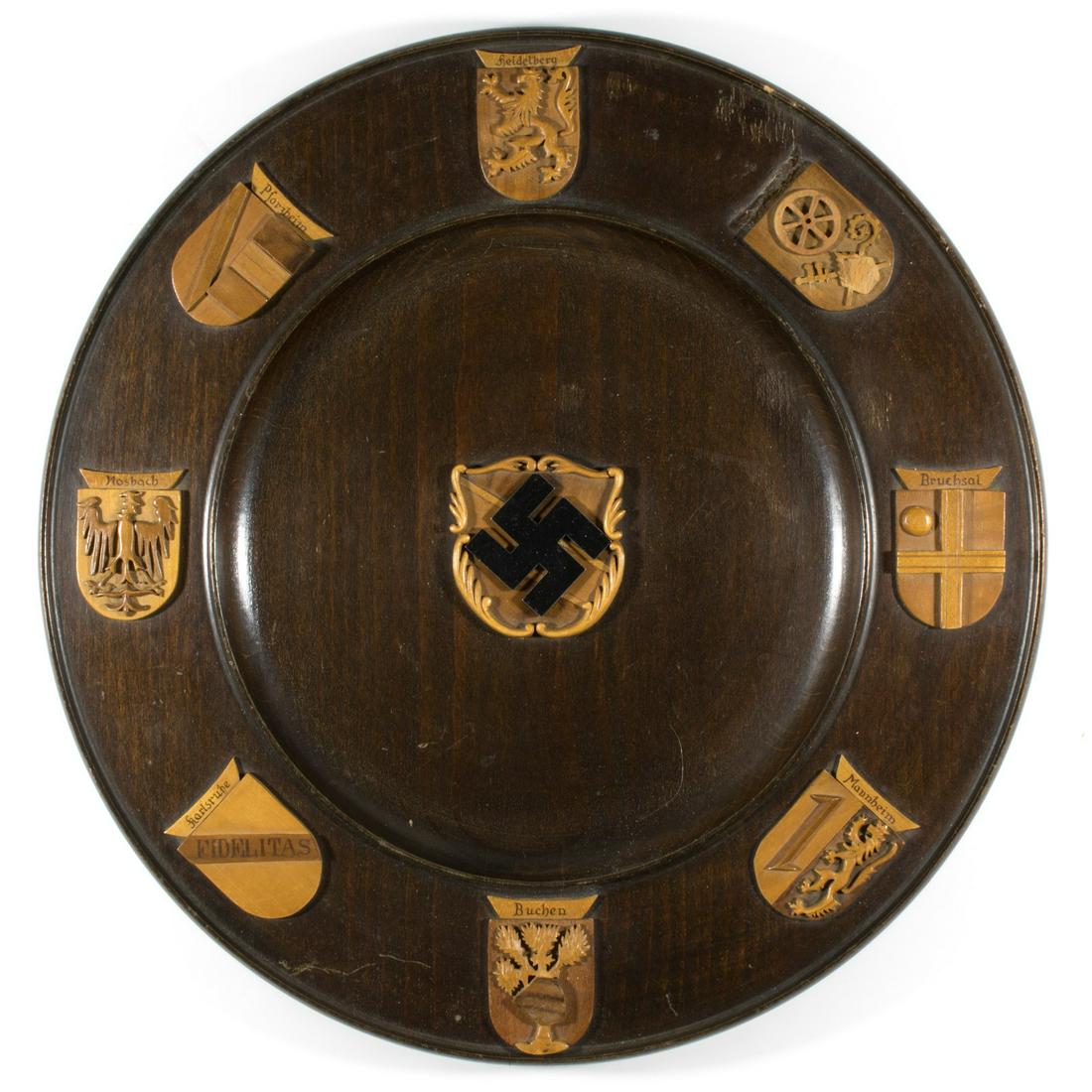 NAZI DECORATIVE WOOD PLAQUE: Very well crafted turned wood plaque, 15 in. diameter, which originally was displayed in a German army hospital in Heidelberg. The plaque is finished with a dark oak stain and is embellished with the