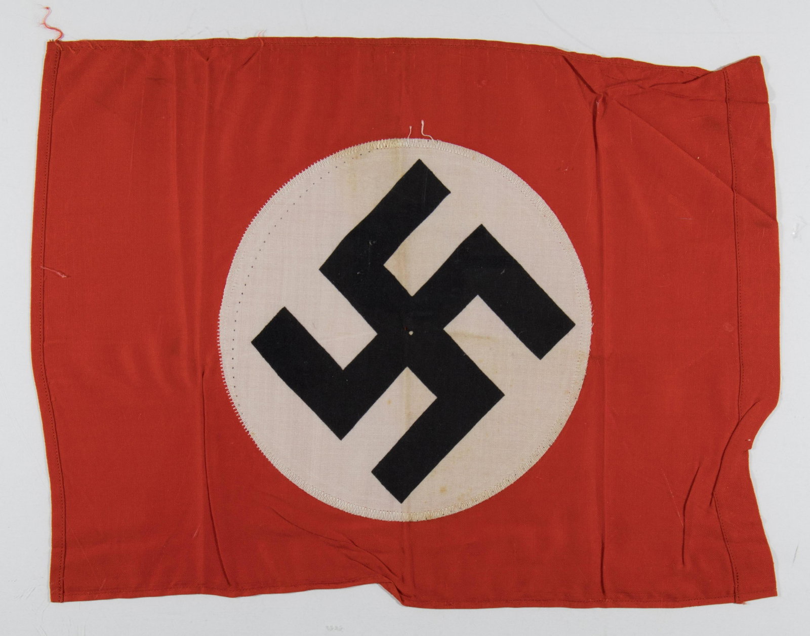 NAZI PARTY FLAG: Small double-sided cotton construction Nazi Party flag, 14.5 x 11.5 in., bearing a red field with a printed black swastika on a sewn-on white disc. A few minor stained spots and a trivial hole are dis