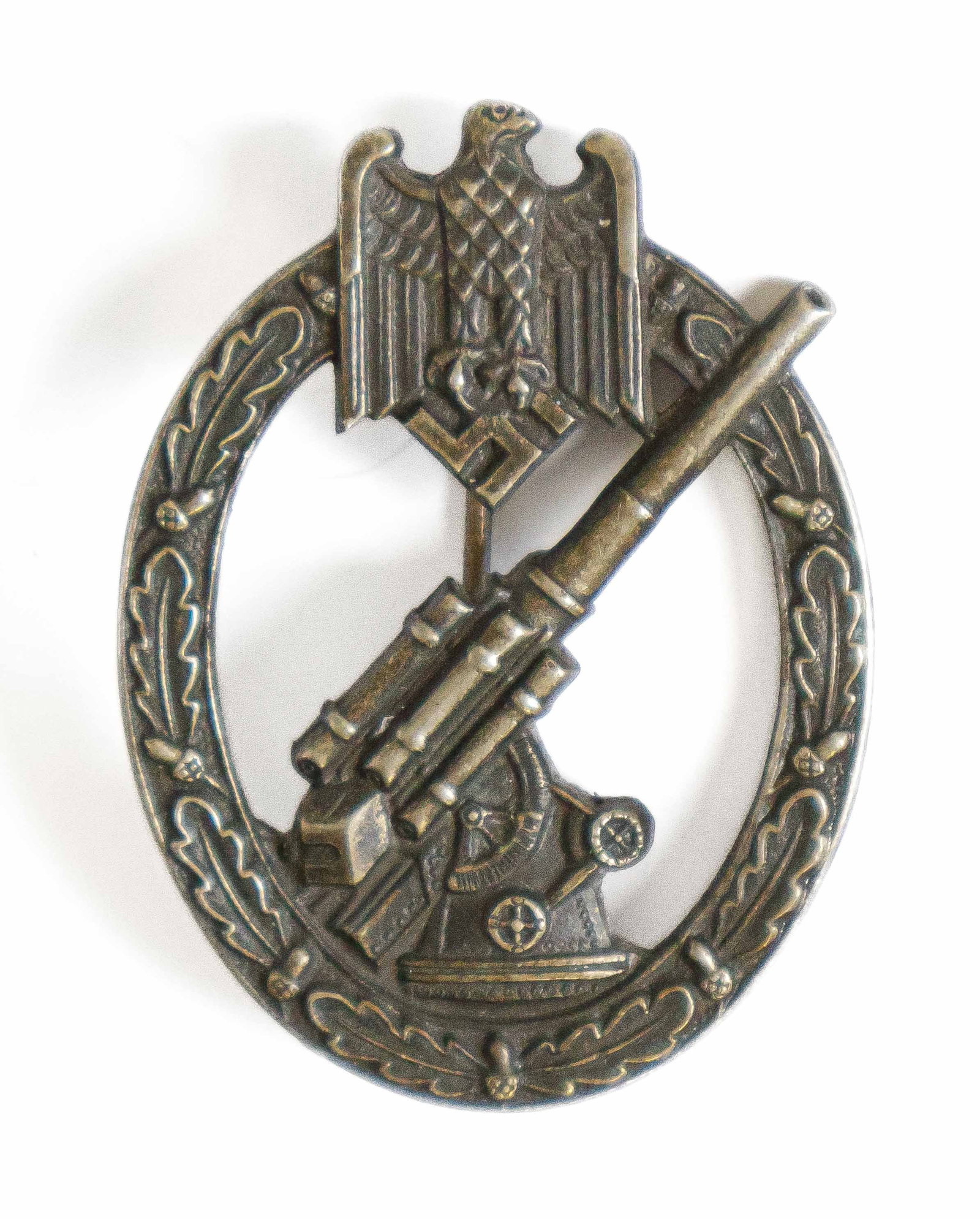 HEER FLAK BADGE: Heer flak badge of zinc construction, 1.5 x 2.25 in., depicting an 88mm gun resting on a gun emplacement, surrounded by an oakleaves wreath, with a ‘Reichsadler’ eagle clutching a mobile s
