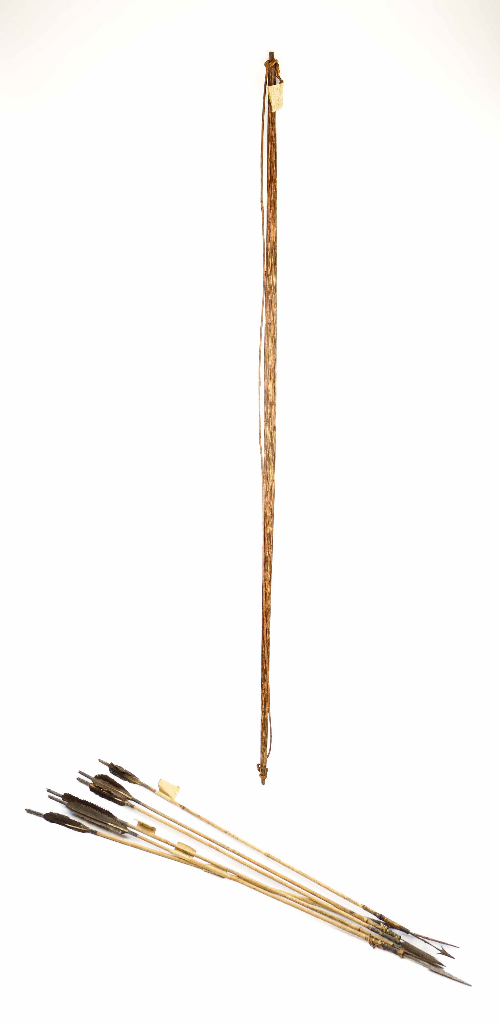 VINTAGE FILIPINO BOW AND ARROWS: Finely crafted bow, 67 in. long, World War II era, with a string fashioned from twisting tree bark from a binuag tree. Accompanied by six arrows made from bayto reeds with feather fletching. Attached