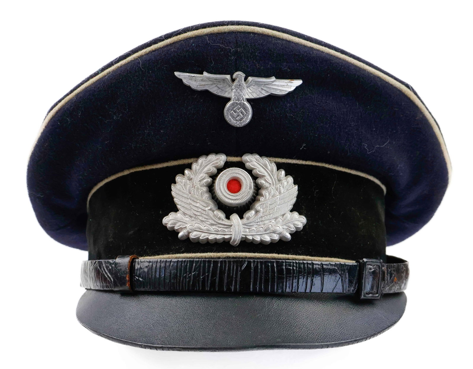 ‘BAHNSCHUTZPOLIZEI’ RAILWAY PROTECTION POLICE OFFICER’S VISOR CAP: Railway Protection Police Non-commissioned Officer’s visor cap of navy blue wool construction with a black doeskin wool band and white wool piping. Affixed to the band is a multi-piece insignia 