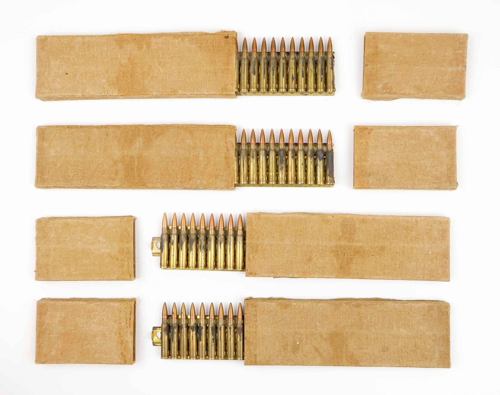 JAPANESE 7.7 MACHINE GUN BOXED AMMO: Grouping of four 30-round boxes of ammunition for a Japanese 7.7mm machine gun. The three cartridges are loaded onto a brass Hotchkiss feed strip and held within muslin-covered boxes. This ammo was de