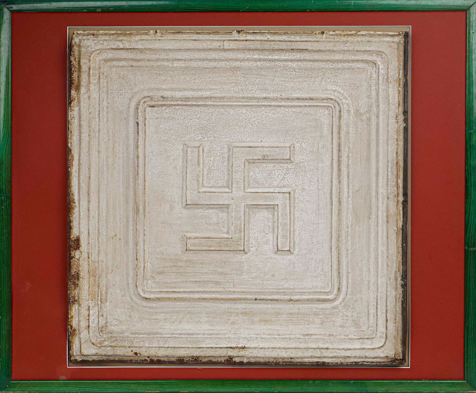 VINTAGE CEILING TILE WITH SWASTIKA: A vintage painted tin tile, 24 x 24 in., with a bas-relief swastika at the middle and painted white. It is reputed to have hung from the ceiling of an east coast German American Bund headquarters, but