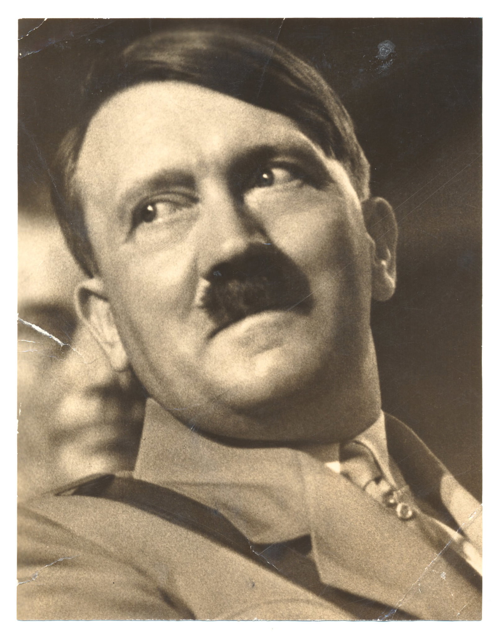 ADOLF HITLER: An original photograph 5 x 6.5 in. b/w, a close-up portrait of Hitler in his younger years, trimmed from a larger image. Small tear at the left edge, creasing and light wear, still good condition.