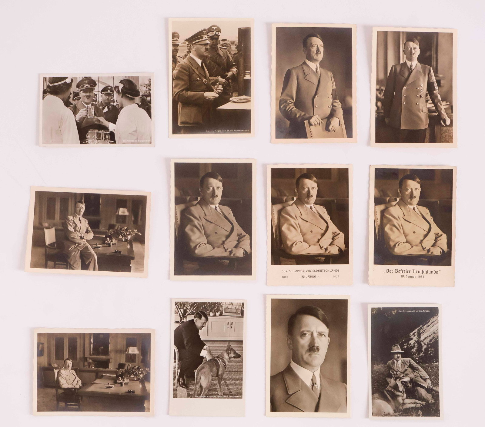 ADOLF HITLER (12): Excellent selection of 12 fine postcard photographs of Hitler as Chancellor, showing him in formal poses, with his dog Blondi, enjoying a glass of beer as a disapproving Himmler looks on, etc. Fine co