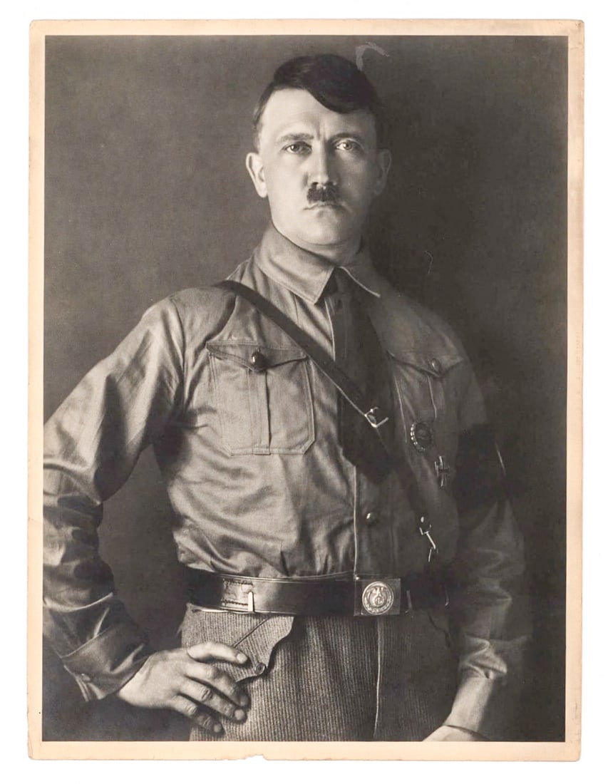 ORIGINAL HOFFMAN PHOTOGRAPH OF ADOLF HITLER: Early original photograph, 7 x 9.5 in., portrait photo of Adolf Hitler taken by his personal photographer Heinrich Hoffman. Hitler is shown in his S.A. uniform and corduroy pants, displaying his Iron
