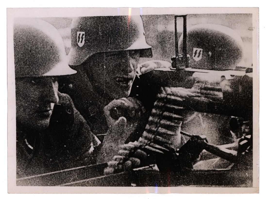 SS MACHINE GUN TEAM IN ACTION: Acme press photograph, 7 x 9 in. b/w, purportedly showing a scene from '...'War in the East,' Nazi horror film of the German campaign in Soviet Russia...', depicts three determined SS machine gunners.