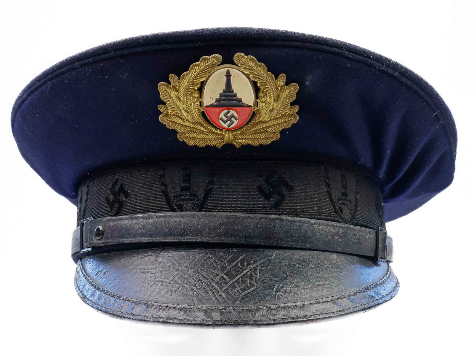 KYFFHAUSERBUND VISOR CAP: Wool construction with attractive woven sideband bearing swastikas and the organization's enameled DRKB monument, with wreath (lacking cockade). Interior lined in silk with silver embossed logo, with 