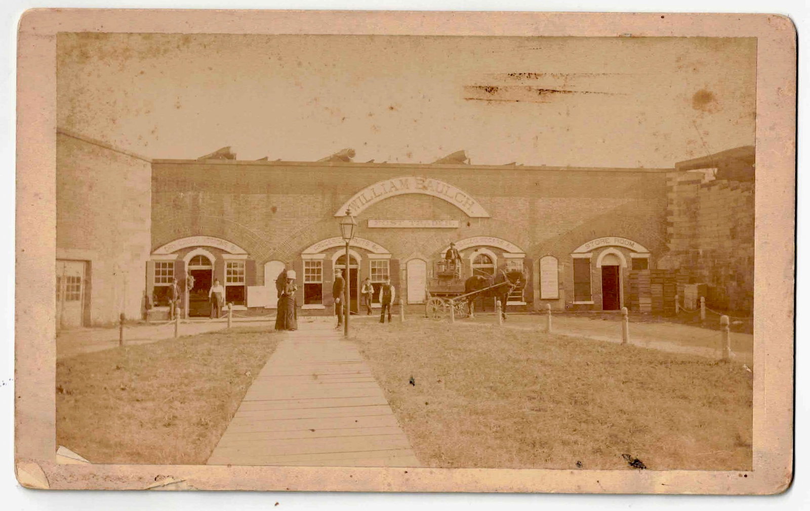 SUTLER AT FORTRESS MONROE: Original photograph, 8 x 5 in. overall, showing the store of sutler William Baulch at Fortress Monroe, Va. A Black wagon driver can be seen atop the wagon at the center which bears the store's name, a