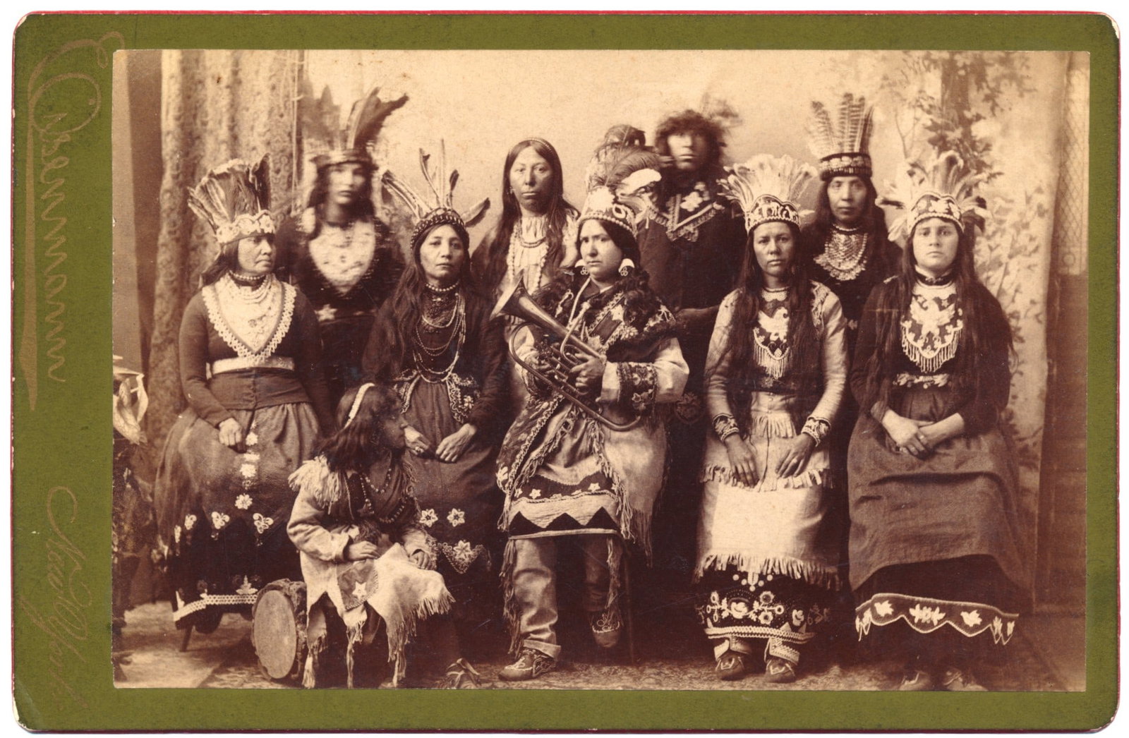 NATIVE AMERICAN WOMEN: Cabinet photograph, 6.5 x 4.25 in., depicts a group of Native American women (or possibly South American) in full regalia, one clutching a French horn. Credited to Chas. Eisenmann, New York on verso. 