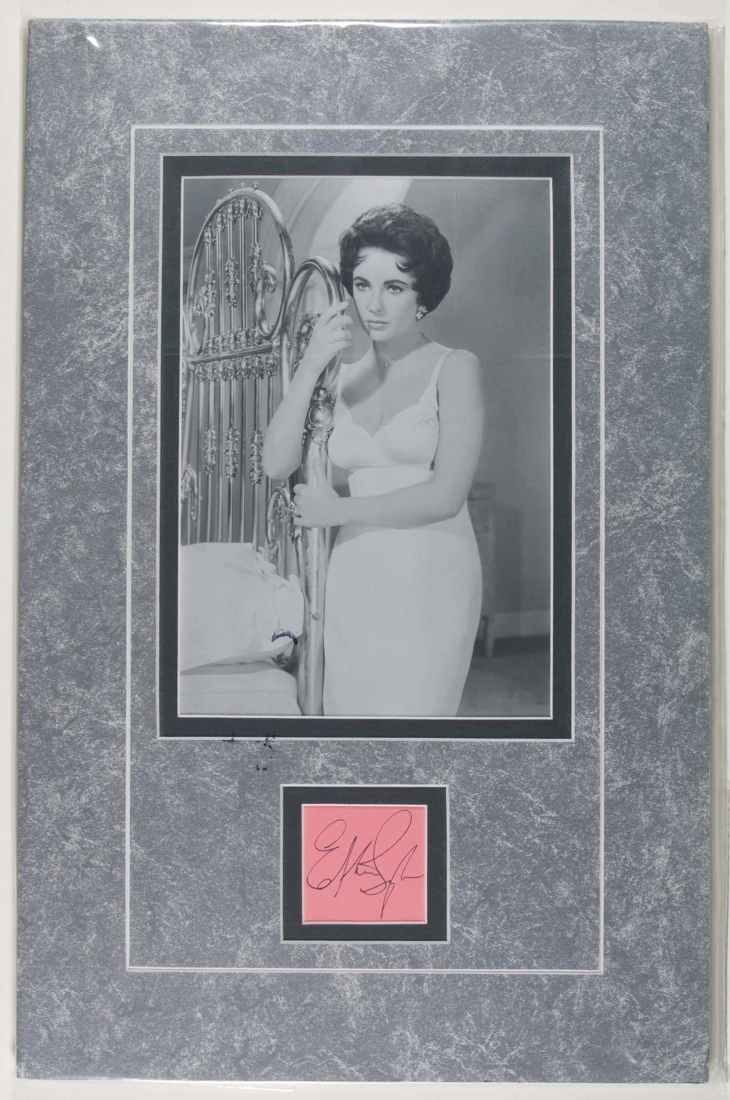 ELIZABETH TAYLOR: (1932 - 2011) American actress, a glamorous leading lady and winner of two Academy Awards for Best Actress. Her black ink signature cut from a pink album page, 2 x 2 in. (sight), double-matted beneath