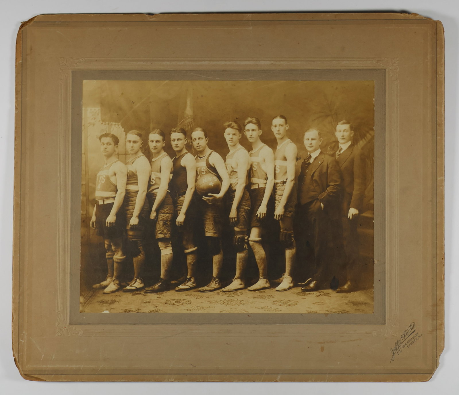 EARLY BASKETBALL PHOTOGRAPH: Early photograph of an unknown New York basketball team taken in Camden, NJ, 14 x 12 in. overall. Edges of the mount are worn and chipped in places, the photo itself very good.
