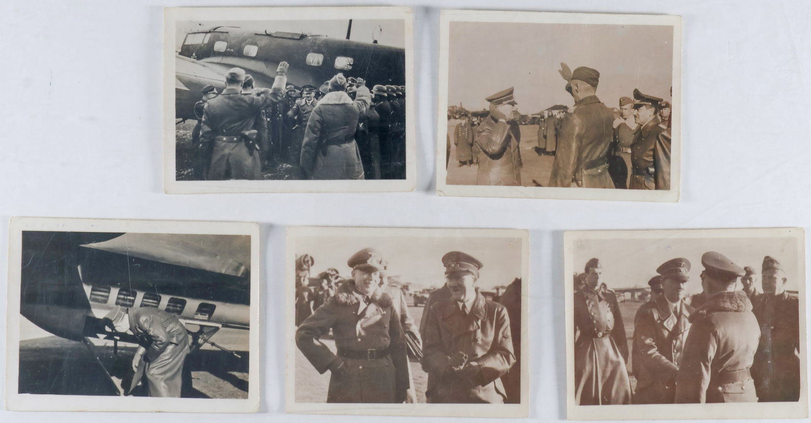 (ADOLF HITLER): A fine group of five original photographs showing Hitler on an airfield with soldiers and generals, and one of the Fuhrer inspecting a plane. Each photo measures 3.75 x 3 in. Three photographs are par